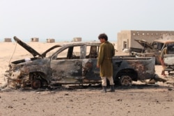 A Yemeni southern separatist fighter inspects the wreckage of government forces vehicles destroyed by UAE airstrikes near Aden, Aug. 30, 2019.