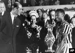 La reina Isabel II y el príncipe Felipe entregan trofeo a la estrella del fútbol Pelé en visita a un estadio en Río de Janeiro, Brasil, el 10 de noviembre de 1968, la monarca estuvo del 5 al 11 de ese mes en visita de Estado.