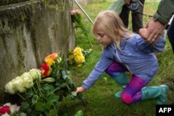 Mtoto anaweka maua kwenye bustani ya Kasri ya Holyroodhouse huko Edinburgh, Scotland, on Sept. 8, 2022, baada ya kutangazwa kifo cha Malkia Elizabeth II.