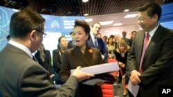 2015年10月21日，中國國家主席習近平夫婦訪問倫敦帝國理工學院期間，中國第一夫人彭麗媛在接受贈送的禮物。（美聯社照片）