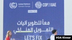 អ្នកចូលរួមកំពុងដើរកាត់ផ្ទាំងបដាអំពីកម្មវិធីសន្និសីទស្តីពីការប្រែប្រួលអាកាសធាតុរបស់អង្គការសហប្រជាជាតិ ឬ COP28 នៅទីក្រុងឌូបៃ ប្រទេសអេមីរ៉ាតអារ៉ាប់រួមកាលពីថ្ងៃទី១ ខែធ្នូ ឆ្នាំ២០២៣។ (កាន់ វិច្ឆិកា/វីអូអេ)