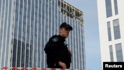 បុគ្គលិក​សន្តិសុខ​មួយ​រូប​ឈរ​យាម​នៅ​ក្បែរ​អគារ​មួយ​កន្លែង​ ដែល​ត្រូវ​ខូចខាត​ដោយ​អ្វី​ដែល​គេ​គិត​ថា​ជា​ការ​វាយប្រហារ​តាម​ដ្រូន នៅ​ទី​ក្រុង​មូស្គូ ប្រទេស​រុស្ស៊ី កាល​ពី​ថ្ងៃ​ទី​២៤ ខែ​កក្កដា ឆ្នាំ​២០២៣។