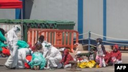 Wahamiaji waonekana kwenye bandari ya Los Cristianos wakihudumiwa na wafanyakazi wa dharura baada ya kuokolewa kwenye pwani ya kisiwa cha Canary, Machi 26, 2022. 