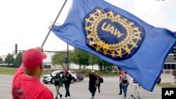 Members of the United Auto Worker Union walk out of the Chicago Ford Assembly Plant as Lance Williams from Lansing, Ill., waves the UAW flag Sept. 29, 2023, in Chicago.
