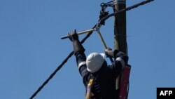 fundi umeme akifanya matengenezo katika nguzo ya umeme 