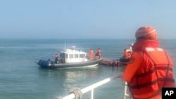 In this handout photograph provided by Taiwan Coast Guard Administration, Taiwanese coast guards inspect a vessel that capsized during a chase off the coast of Kinmen archipelago in Taiwan, Feb. 14, 2024. 