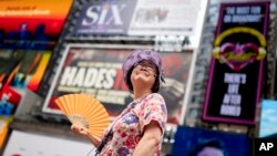 Una guía turística se abanica mientras trabaja en Times Square mientras aumentan las temperaturas, el 27 de julio de 2023, en Nueva York. 