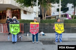 កូដករណាហ្គាវើលដ៍ឈរលើកបដាតវ៉ានៅពីមុខក្រុមហ៊ុនណាហ្គាវើលដ៍ ក្នុងរាជធានីភ្នំពេញ កាលពីថ្ងៃទី២៥ ខែកុម្ភៈ ឆ្នំា២០២៤។ (ស៊ឹម ចាន់សំណាង/វីអូអេ)