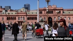 Ciudadanos pasean frente a la sede del Poder Ejecutivo, la Casa Rosada, en Buenos Aires, a escasas horas para la toma de posesión de Javier Milei.