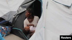 Una mujer sostiene a un bebé mientras ella y otras personas se refugian en un estadio deportivo después de huir de la violencia de las pandillas, en Puerto Príncipe, capital de Haití, el 1 de septiembre de 2023.