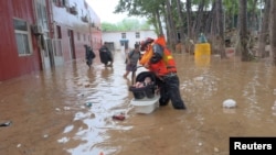 中国救援人员在房山县救助疏散受到洪水袭击的一名幼童。（2023年7月31日）