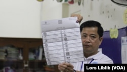 មន្ត្រីរៀបចំការបោះឆ្នោត ក្នុងមណ្ឌលមួយក្នុងរាជធានីភ្នំពេញ លើកបង្ហាញ​សន្លឹកឆ្នោត​ដែល​ត្រូវបាន​គូស​ចោល និងរាប់ នៅថ្ងៃទី២៣ ខែមិថុនា ឆ្នាំ២០២៣។ (លាស់ លីបលីប/វីអូអេ)