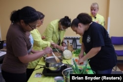 Jelainie and her mother make a vegetable dish with Holyoke Health Center staff, Massachusetts, June 11, 2024. (REUTERS Photo/Brian Snyder)