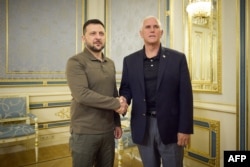 На цій роздатковій фотографії, зробленій та оприлюдненій прес-службою президента України в Києві 29 червня 2023 року, президент України Володимир Зеленський (ліворуч) і колишній віце-президент США Майк Пенс потискають один одному руки перед зустріччю.