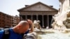 Seorang pria mendinginkan diri di air mancur dekat Pantheon, saat gelombang panas melanda Italia, di Roma, 19 Juli 2023. (Foto: Reuters)
