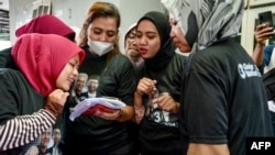 FILE - Para pendukung capres-cawapres Ganjar Pranowo dan Mahfud MD, tengah menonton video media sosial yang menampilkan mereka di platform TikTok Ukon Furkon Sukanda, di Tangerang, Banten, 10 Januari 2024.(BAY ISMOYO / AFP) 