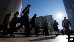 Commuters walk in a passageway during a rush hour at Shinagawa Station Wednesday, Feb. 14, 2024, in Tokyo. (AP Photo/Eugene Hoshiko)