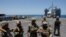 FILE - U.S. soldiers stand at Trident Pier, a temporary pier to deliver aid, off the Gaza Strip, amid the ongoing conflict between Israel and Hamas, near the Gaza coast, June 25, 2024, as an aid truck drives off a ship in the background.