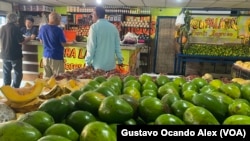 Clientes hacen fila para pagar sus compras de comida en una venta de frutas, vegetales y víveres en Maracaibo, Venezuela.