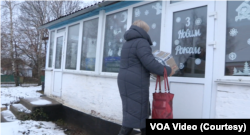 Директорка Стодулецької сільської бібліотеки Леся Оранська заносить пакунок із книгами у приміщення бібліотеки