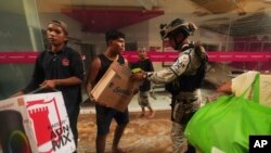 Un miembro de la Guardia Nacional ofrece asistencia a los damnificados tras el devastador paso de Otis.