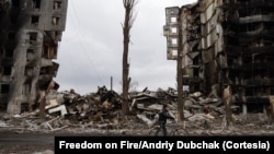 En una de las escenas del documental Freedom on Fire (Libertad en llamas) un hombre camina con su bicicleta entre las ruinas de los edificios bombardeados en la región del Donbás.