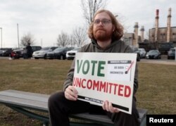 Sukarelawan "Listen To Michigan" Eric Peter-Bull duduk di luar tempat pemungutan suara, sambil memegang tanda yang mendorong orang untuk memilih tanpa komitmen pada pemilihan presiden pendahuluan di Dearborn, Michigan, AS 27 Februari 2024. (REUTERS/Rebecca Cook)
