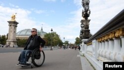 ฟรองค์ เมลล์ วัย 52 ปี จากกลุ่มรณรงค์เพื่อคนพิการ APF France เขาต้องนั่งรถเข็นวีลแชร์มาทั้งชีวิต เดินทางมา ณ Pont Alexandre III bridge ในกรุงปารีส ฝรั่งเศส เมื่อ 30 สิงหาคม 2023 เพื่อสะท้อนวิถีชีวิตของผู้ใช้รถเข็นผู้ป่วยในการสัญจรทั่วกรุงปารีส (รอยเตอร์)