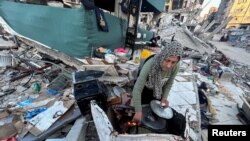 Perempuan Palestina Umm Nael Al-Khlout memasak sarapan di atas puing-puing rumahnya yang hancur akibat serangan militer Israel, di Beit Lahia, Jalur Gaza utara, 13 Maret 2024. (REUTERS/Mahmoud Issa)