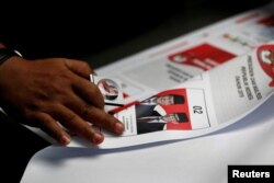 Seorang pekerja menggunakan kaca pembesar saat memeriksa surat suara yang dicetak untuk pemilihan presiden mendatang di sebuah pabrik di Jakarta, 20 Januari 2019. (Foto: REUTERS/Willy Kurniawan)