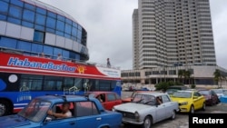 Un autobús turístico pasa junto a los automóviles que hacen fila para llenar sus tanques de gasolina en La Habana, Cuba, el 11 de diciembre de 2023.