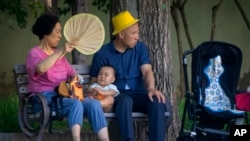 北京公園裡一對老夫婦和一名幼兒在乘涼。 （2023年6月29日）