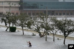 Zeke Pierce rides his paddle board down the middle of a flooded Bayshore Blvd in downtown in Tampa, Fla., Wednesday, Aug. 30, 2023. Hurricane Idalia steamed toward Florida’s Big Bend region Wednesday morning, threatening deadly storm surges and destructive winds in an area not accustomed to such pummeling. (AP Photo/Chris O'Meara)