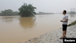 A resident looks on as he stands near a flooded river following heavy rainfall in Qingyuan, Guangdong province, China, April 22, 2024. 