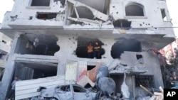 Palestinos dentro de un edificio destruido en un ataque aéreo israelí en el campamento de Nuseirat en el centro de la Franja de Gaza, el lunes 16 de octubre de 2023. [AP]