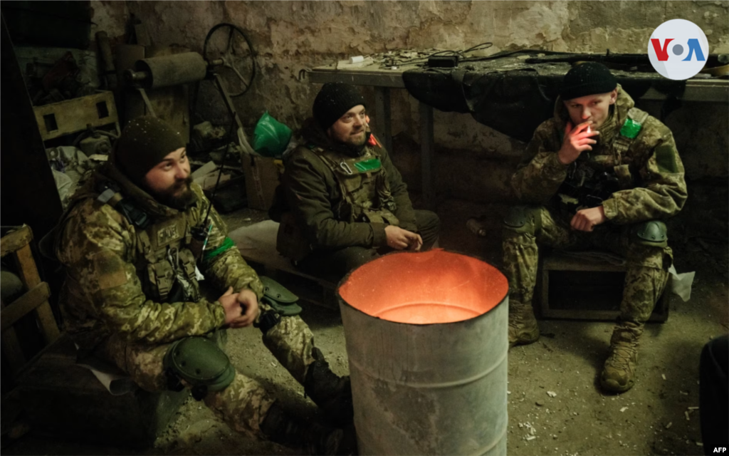 Morteros se calientan junto al fuego en un refugio mientras esperan la próxima oportunidad para enfrentarse al enemigo.