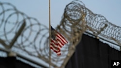 FILE - A flag flies at half-staff in honor of slain U.S. service members and other victims of terrorism, as seen from Camp Justice in Guantanamo Bay Naval Base, Cuba, Aug. 29, 2021.