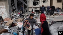 Palestinos recuperan sus pertenencias después de un ataque israelí en Kahan Younis, Franja de Gaza, el viernes 12 de enero de 2024. 