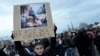 A woman holds up a placard depicting French President Emmanuel Macron sitting on garbage cans, during a protest against pension reform, in Paris, March 17, 2023. The placard reads "King of Trash."