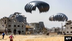 Луѓе брзаат дo пакети со хуманитарна помош фрлени над северниот дел на појасот Газа на 23 април 2024 година