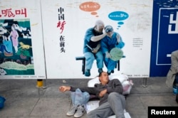 一名農民工在北京火車站的一個中國夢的政府宣傳牌下打盹。