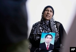 Nidal Ali holds a photo of her missing son in Mahmoudiya, south of Baghdad, Iraq, Tuesday, March. 28, 2023.