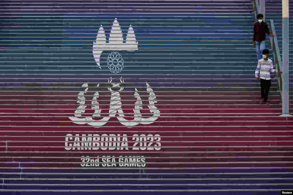 អ្នកទស្សនាពីរនាក់ដើរកាត់បដានៃការប្រកួតកីឡាស៊ីហ្គេមលើកទី ៣២ នៅពហុកីឡដ្ឋានជាតិមរតកតេជោ ក្នុងរាជធានីភ្នំពេញ កាលពីថ្ងៃទី ២ ខែឧសភា ឆ្នាំ ២០២៣។&nbsp;