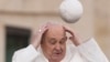 El papa Francisco intenta agarrar su gorra cuando el viento se la lleva mientras llega a su audiencia general semanal en la Plaza de San Pedro en el Vaticano, el 13 de marzo de 2024.