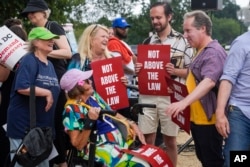 Demonstranti drže natpise "Ne iznad zakona" dok se okupljaju 3. avgusta 2023. u Washingtonu.