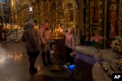 Orthodox Christian worshipers light candles during an Easter Sunday service in Kyiv, Apr. 16, 2023.