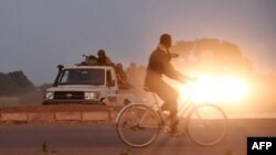 Un homme chevauche des gendarmes alors qu'ils gardent la route menant à la caserne militaire de la garde présidentielle d'élite (RSP), le 29 septembre 2015 à Ouagadougou.