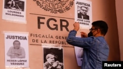 Un hombre coloca carteles que retratan a periodistas asesinados, durante una protesta que exige justicia y protección del gobierno federal tras los asesinatos de cinco colegas, frente a la oficina del Fiscal General en Ciudad Juárez, México, el 14 de febrero de 2022.