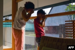 FILE - Cempaka Asriani dan putranya (enam tahun), menderita batuk terus-menerus akibat polusi udara Jakarta, tengah bermain di dalam rumah kediaman mereka, 29 Agustus 2023. (BAY ISMOYO/AFP)