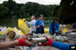 ہنگری کے دریائے ٹسزا سے کشتیوں پر لاد کر لائے گئے کچرے کواکٹھا کیا جا رہا ، فوٹو اے پی ،2 اگست 2023 ۔